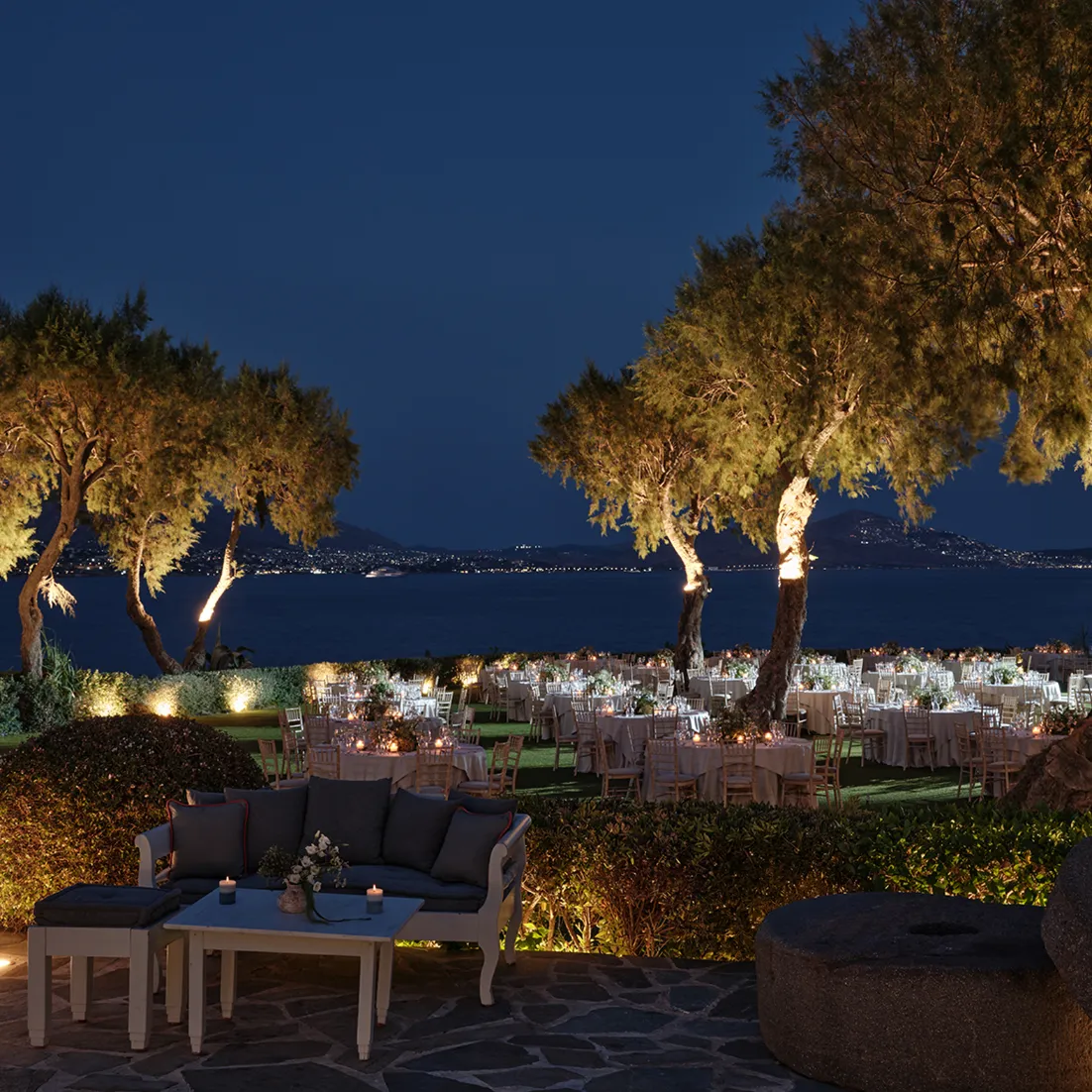 Candlelit seaside reception beneath illuminated trees